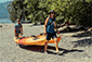 Two people walking on the beach with a kayak, enjoying a Vancouver Water Adventures experience.